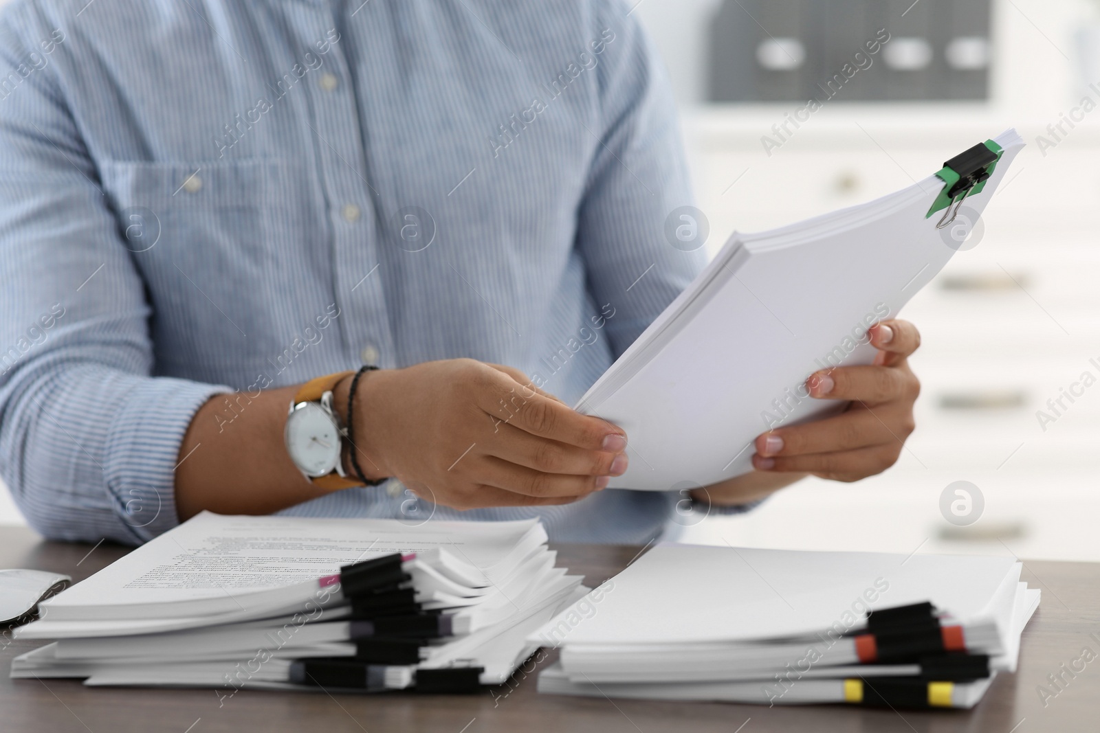 Photo of Man working with documents at wooden table in office, closeup