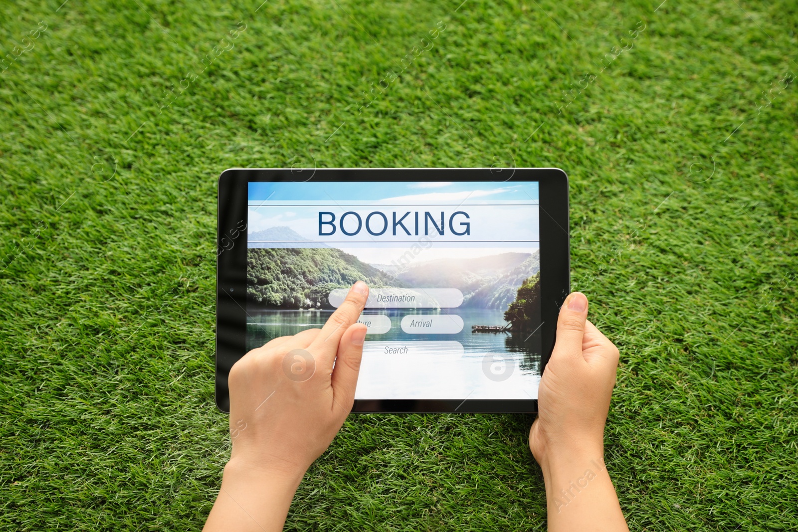 Photo of Woman booking tickets online on green grass, closeup. Travel agency concept