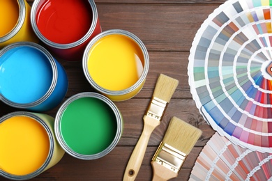 Photo of Flat lay composition with paint cans, brushes and color palettes on wooden background