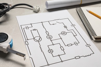 Wiring diagram, wires, tape measure and office stationery on white wooden table, closeup