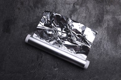 Roll of aluminum foil on grey table, top view