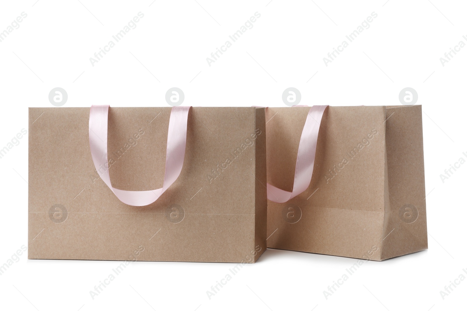 Photo of Paper shopping bags with ribbon handles on white background. Mockup for design