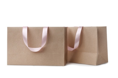 Photo of Paper shopping bags with ribbon handles on white background. Mockup for design