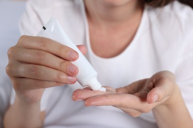 Photo of Woman applying cream from tube on hand, closeup