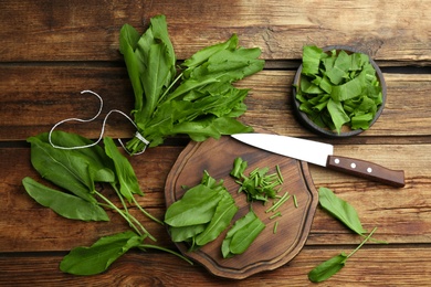 Photo of Fresh green sorrel leaves and knife on wooden table, flat lay