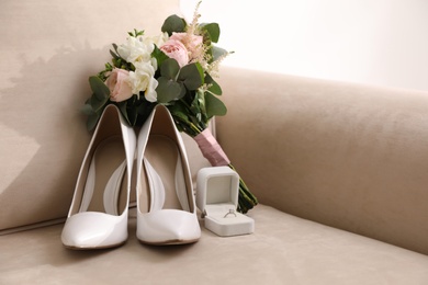 Photo of Composition with white wedding high heel shoes on sofa