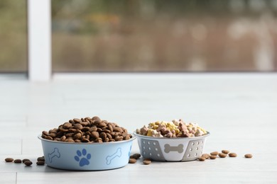 Photo of Bowls with dry dog food on white floor indoors