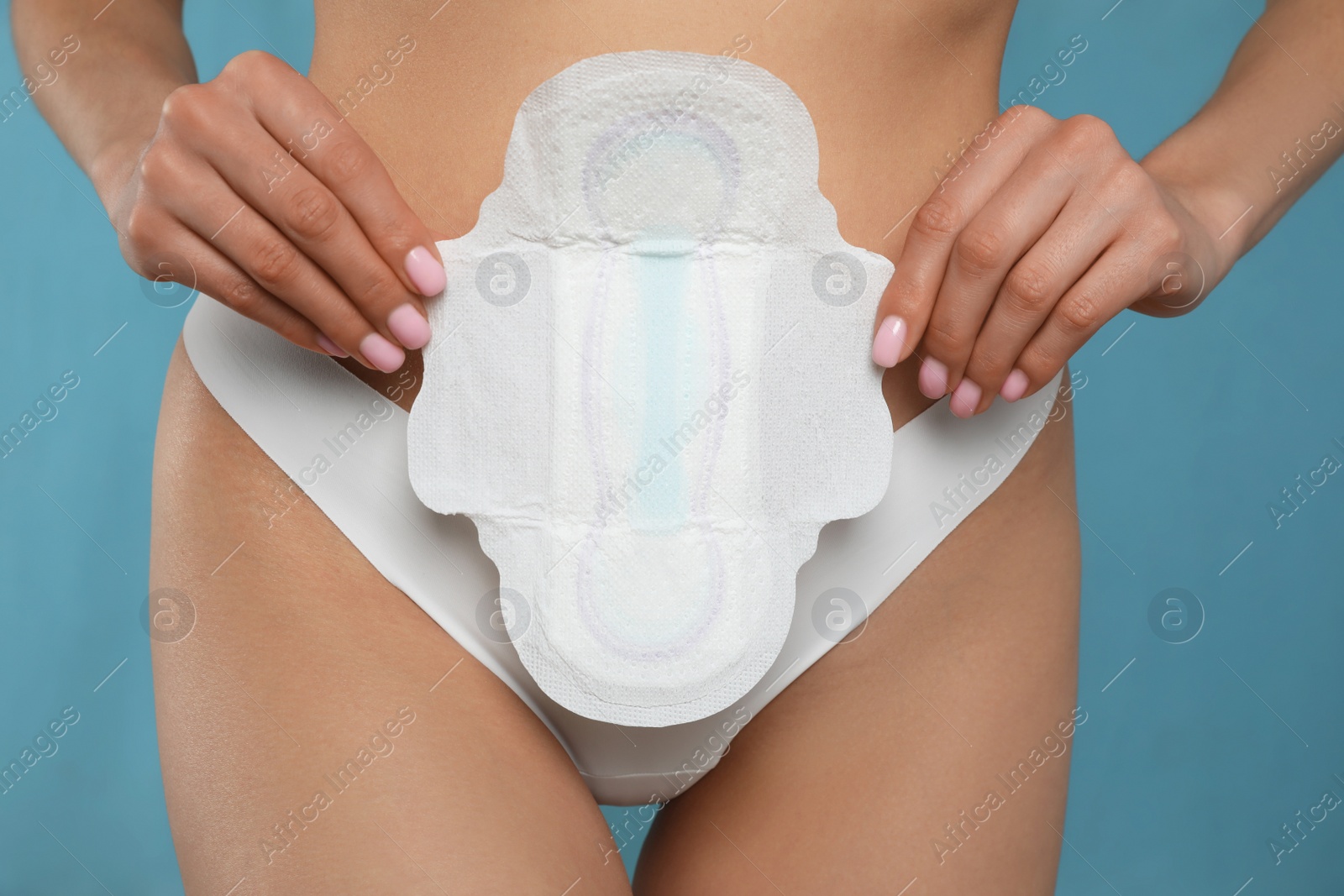 Photo of Woman in white panties with menstrual pad on light blue background, closeup