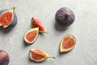 Photo of Flat lay composition with whole and cut purple figs on gray background