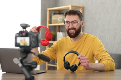 Photo of Smiling technology blogger recording video review about headphones at home