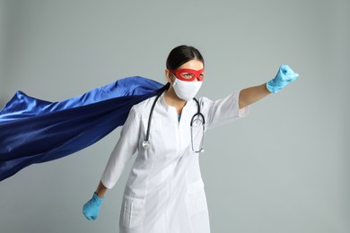 Doctor dressed as superhero posing on light grey background. Concept of medical workers fighting with COVID-19