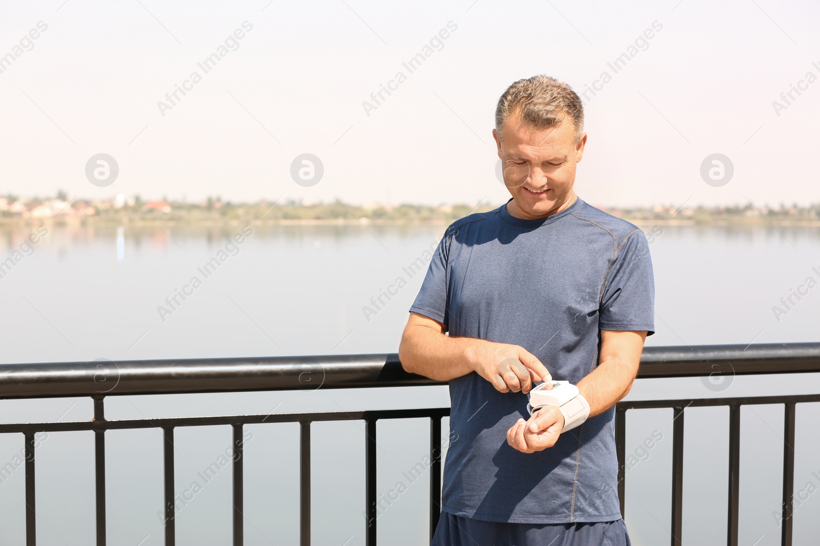 Photo of Man checking pulse outdoors on sunny day