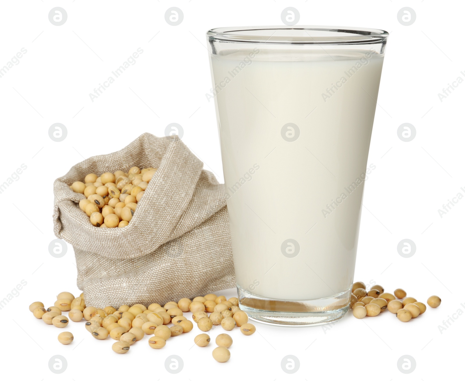 Photo of Glass of fresh soy milk and sack with beans on white background