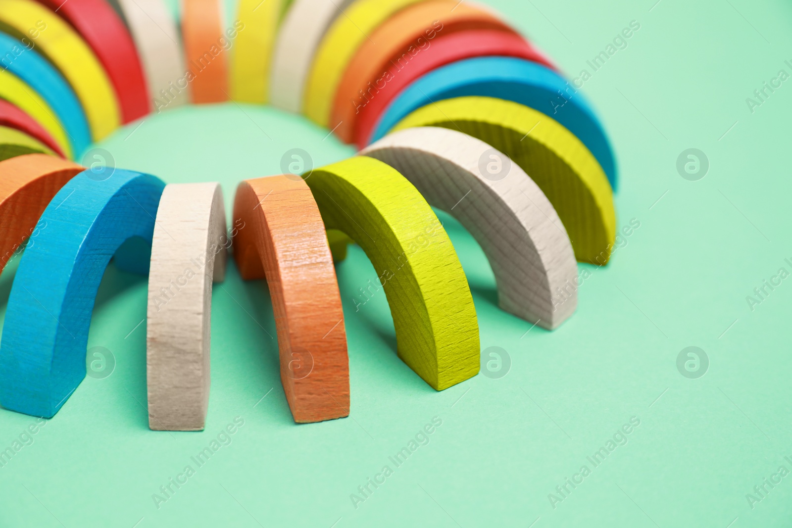 Photo of Colorful wooden pieces of play set on green background, closeup with space for text. Educational toy for motor skills development