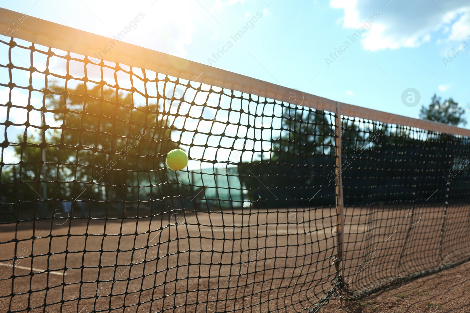 Photo of Bright yellow tennis ball hitting into net on court