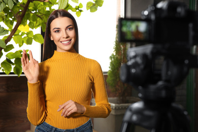 Photo of Young blogger recording video on camera indoors