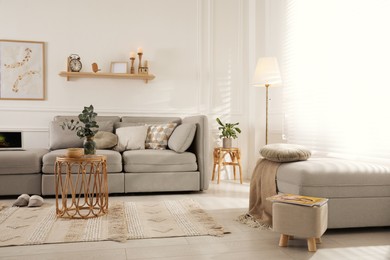 Photo of Living room with comfortable grey sofa, ottoman and stylish interior elements near window