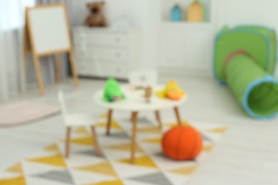 Photo of Blurred view of child`s playroom with different toys and furniture. Stylish kindergarten interior