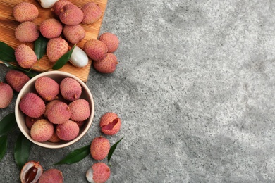 Photo of Fresh ripe lychee fruits on grey table, flat lay. Space for text