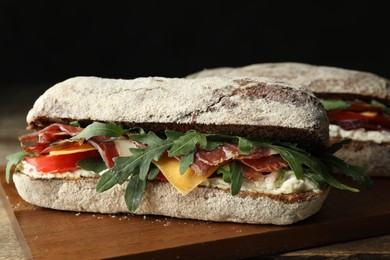 Photo of Delicious sandwich with fresh vegetables and prosciutto on wooden table, closeup