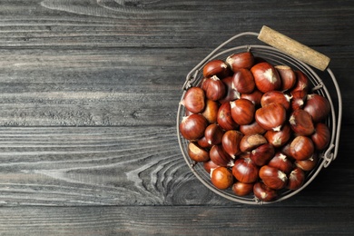 Photo of Fresh sweet edible chestnuts on black wooden  table, top view. Space for text