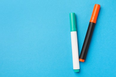 Bright color markers on light blue background, flat lay. Space for text