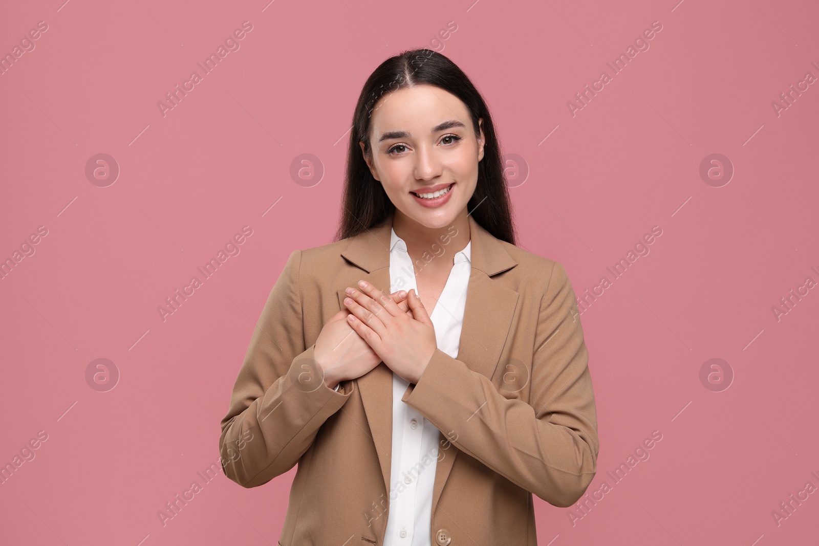 Photo of Thank you gesture. Beautiful grateful woman with hands on chest against pink background