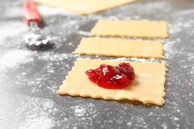 Photo of Preparing delicious ravioli with jam at table, closeup. Tasty pasta