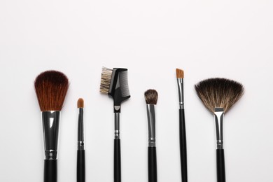 Photo of Set of makeup brushes on white background, flat lay. Space for text