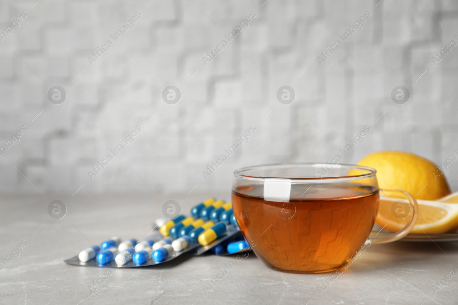 Photo of Cup of hot tea and different cough remedies on table. Space for text