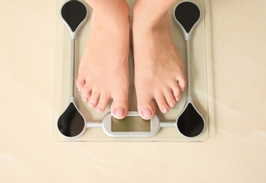 Photo of Woman standing on floor scales indoors, top view. Overweight problem