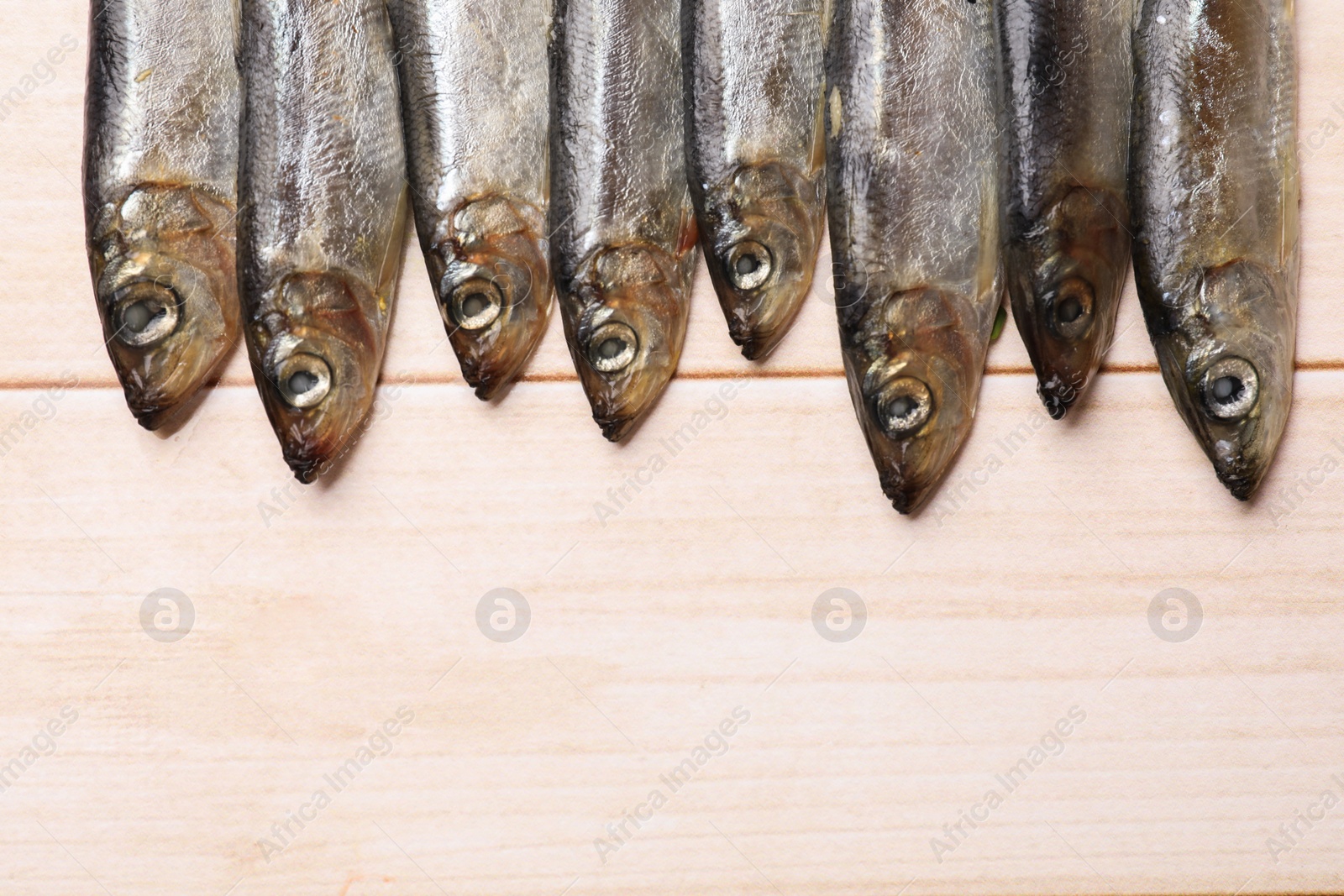 Photo of Fresh raw sprats on light wooden table, top view. Space for text