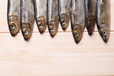 Fresh raw sprats on light wooden table, top view. Space for text