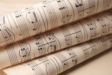 Photo of Rolled sheets with music notes on light background, closeup