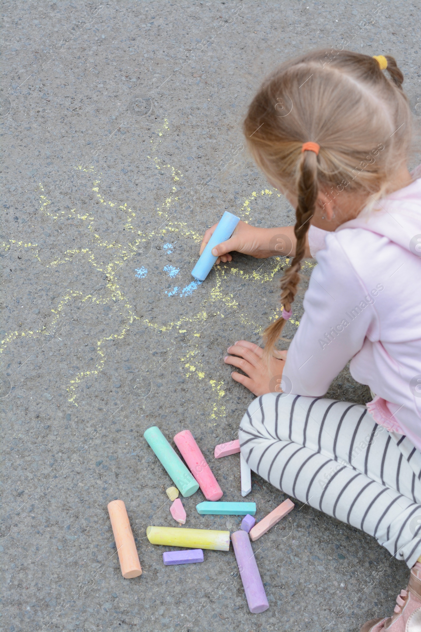 Photo of Little child drawing sun with chalk on asphalt