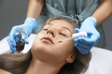 Cosmetologist applying serum on client's face in salon