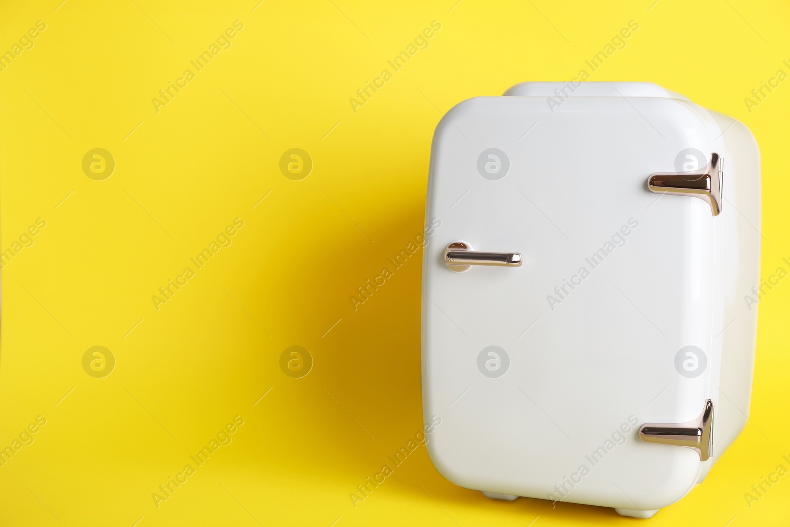 Photo of Cosmetic refrigerator on yellow background, space for text