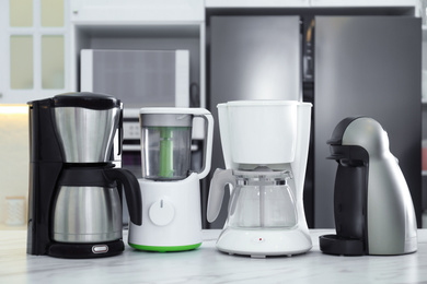 Photo of Set of modern home appliances on white marble table in kitchen