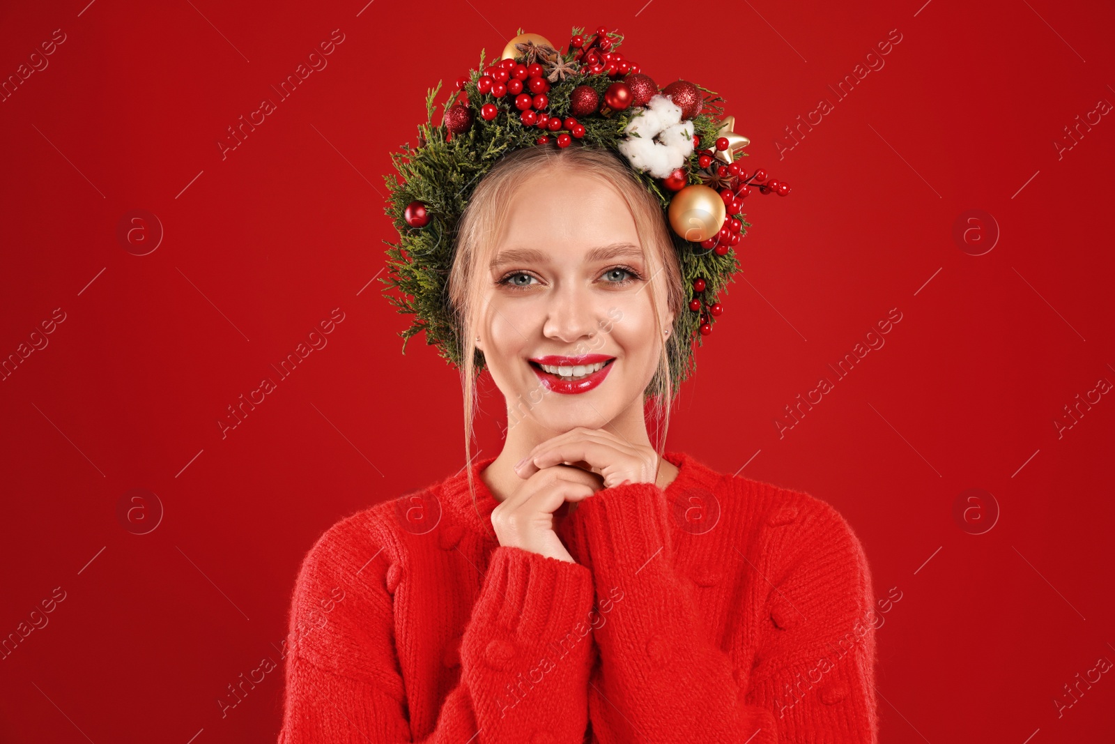 Photo of Beautiful young woman wearing Christmas wreath on red background