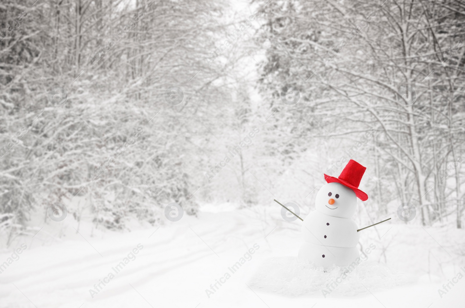 Image of Cute decorative snowman with red hat in snowy forest, space for text