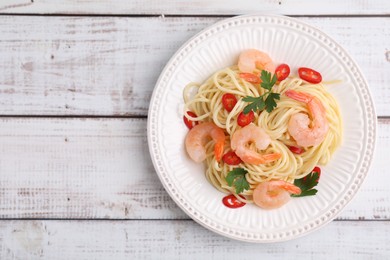 Photo of Tasty spaghetti with shrimps, chili pepper and parsley on wooden rustic table, top view. Space for text