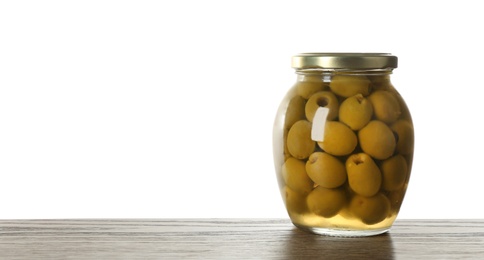 Glass jar of pickled olives on wooden table against white background. Space for text
