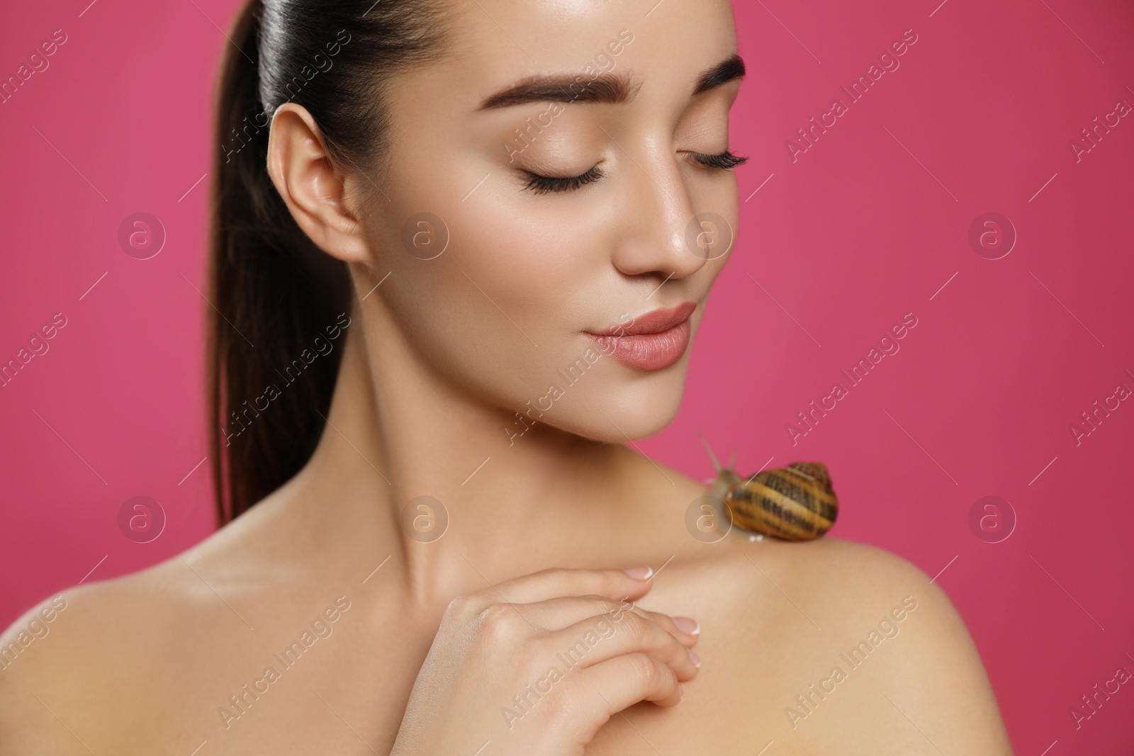 Photo of Beautiful young woman with snail on her shoulder against pink background, closeup