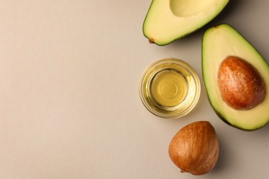 Cooking oil in bowl and fresh avocados on light grey background, flat lay. Space for text