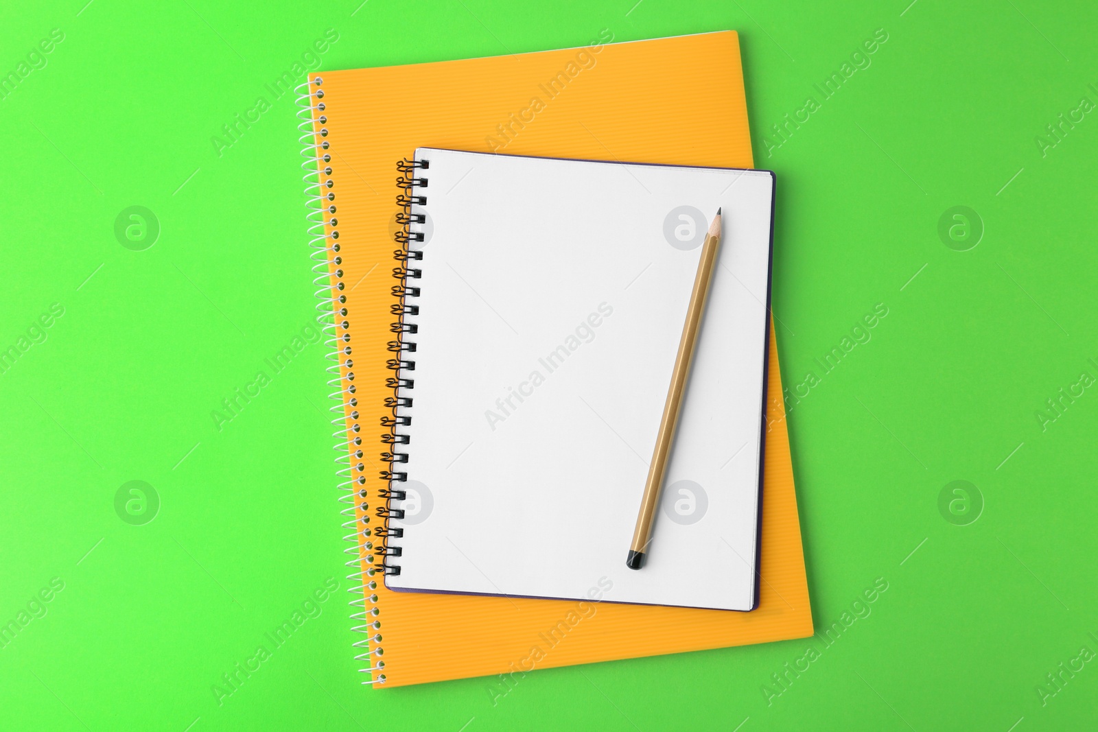 Photo of Notebooks with pencil on light green background, top view