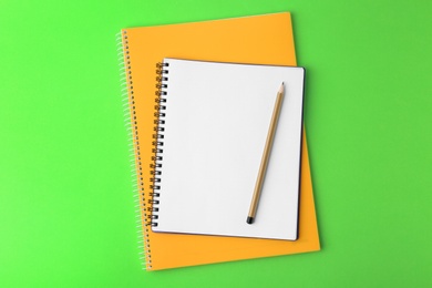 Notebooks with pencil on light green background, top view