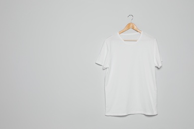 Photo of Hanger with blank t-shirt on gray background. Mock up for design