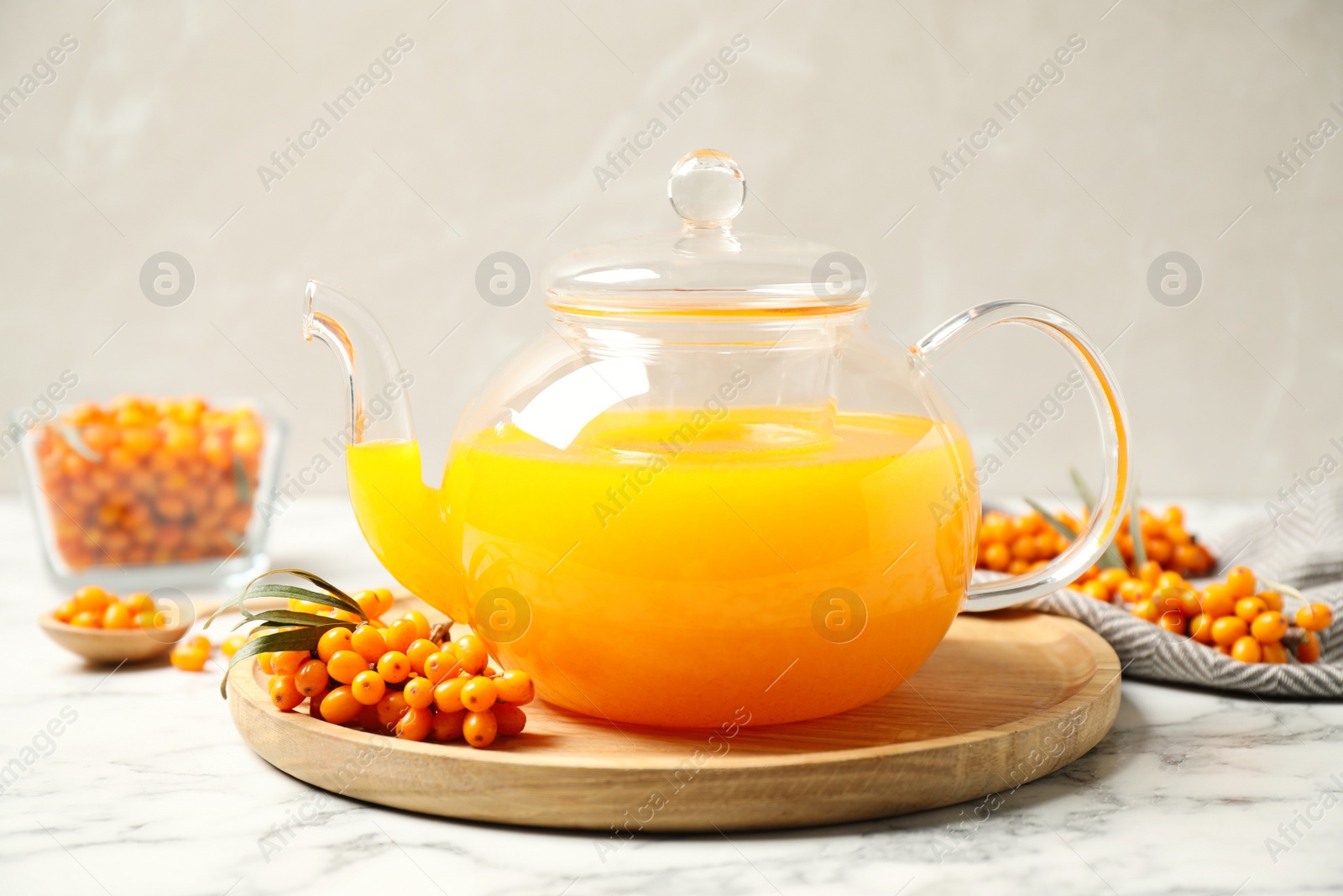 Photo of Delicious sea buckthorn tea and fresh berries on white marble table