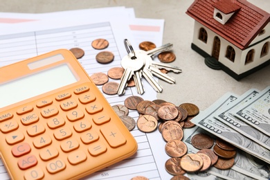 House model with calculator, documents, keys and money on table, closeup. Real estate agent service