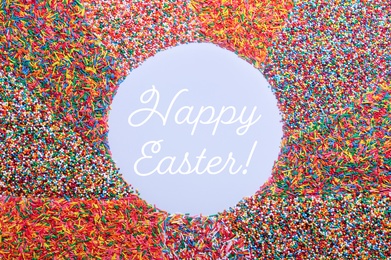 Image of Text Happy Easter and frame of colorful sprinkles on light blue background, flat lay. Confectionery decor